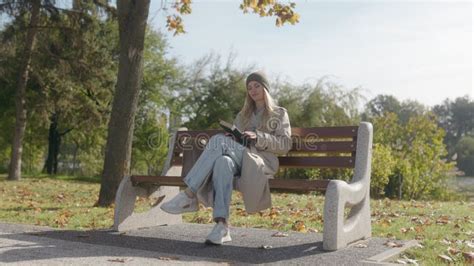 Blonde Woman Reading A Book On A Park Bench Enjoying The Autumn Season Stock Footage Video Of