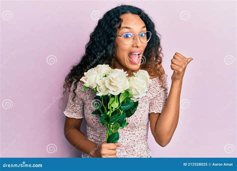 Joven Latina Sosteniendo Flores Apuntando El Pulgar Hacia El Lado