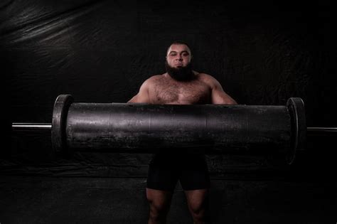 Premium Photo A Powerful Bearded Strong Man Of Arab Appearance With A Naked Torso Lifts An