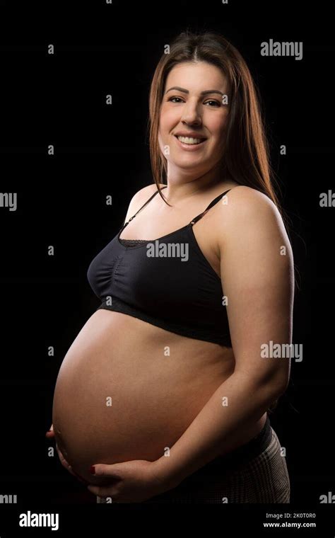 Une Jeune Femme Brunette Aux Derniers Stades De La Grossesse Sourit Et Pose Avec Sa Bosse De