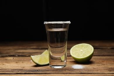 Mexican Tequila Shot With Lime Slice On Wooden Table Against Black