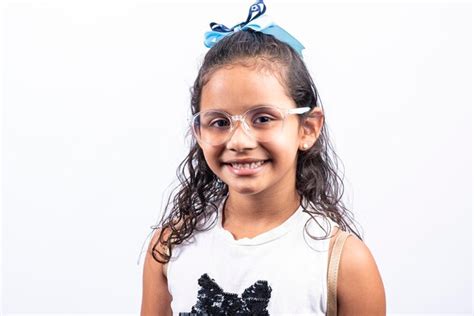 Retrato de una chica latina sonriente con gafas mirando a la cámara sobre un fondo blanco