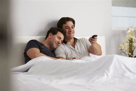 Los Pares Gay Masculinos Se Relajan En La Cama Juntos Que Ve La TV Foto De Archivo Imagen De