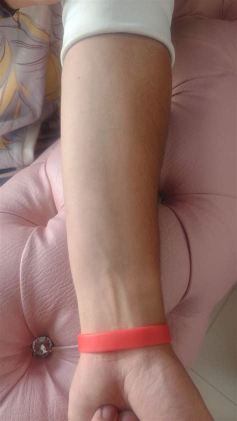 A Person With An Orange Bracelet On Their Wrist Sitting On A Pink