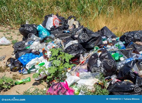 Dump On The River Bank Garbage In Nature Lots Of Black Bags Of Waste