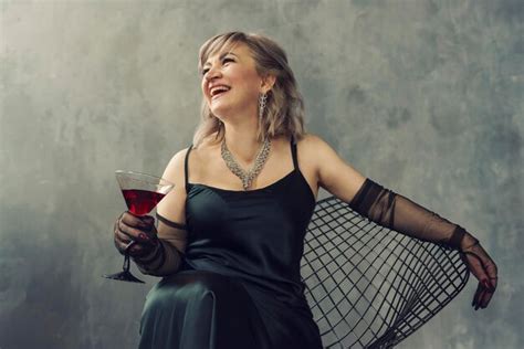 Eine Reiche Blonde Frau In Einem Schwarzen Kleid Und Langen Handschuhen Mit Einem Weinglas Sitzt