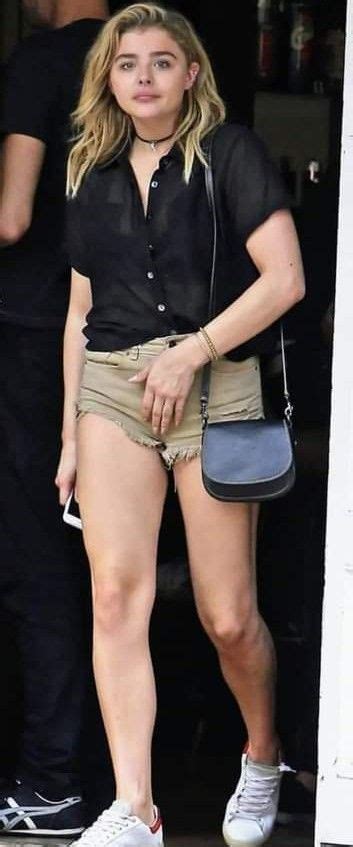 A Woman In Short Shorts And Sneakers Is Walking Out Of A Building With