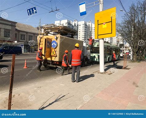 Road Workers in Robes, Overalls and Construction Helmets Work on ...