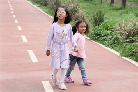 Latina And Year Old Girls Walk Holding Hands Like Sisters And Friends Spending Time Together