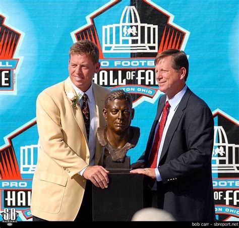 Two Men Standing Next To Each Other In Front Of A Trophy