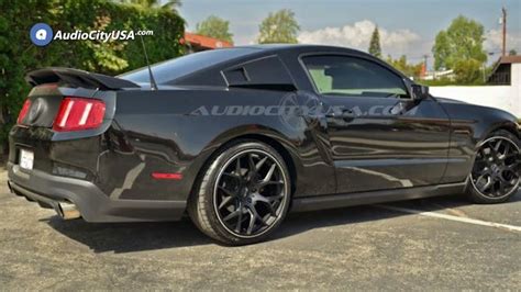 the rear end of a black mustang parked in a parking lot