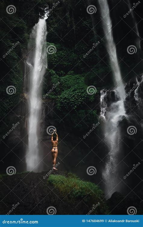 Mujer Joven Hermosa En El Bikini Que Se Relaja Delante De La Cascada