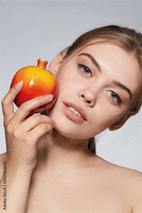 Close Up Portrait Of A Blond Girl With Naked Shoulders She Holding Pomegranate Near Her Cheek