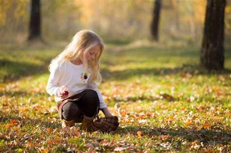 Belle petite fille enfant blonde se promène dans le parc en automne Photo Premium