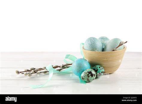 Bowl With Painted Easter Eggs And Pussy Willow On Table Against White