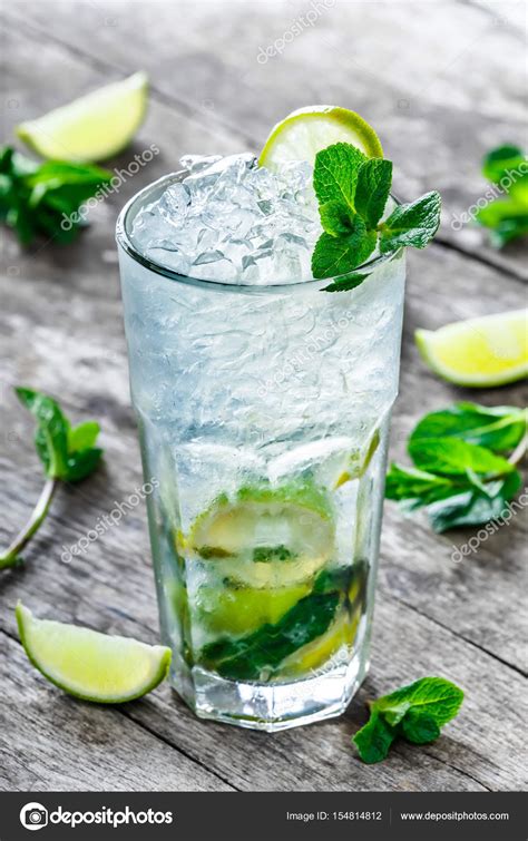 Свежий лимонад мохито с мятой, лаймом и льдом в стекле на деревянном ...