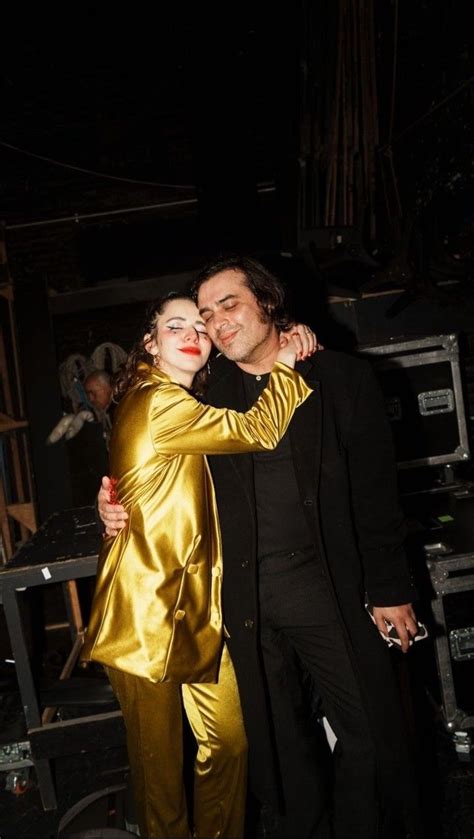 A Man And Woman Dressed In Gold Hugging Each Other