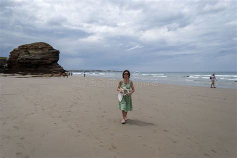 Mature Woman Walking On A Scenic Beach By A Rocky Shoreline Stock Image