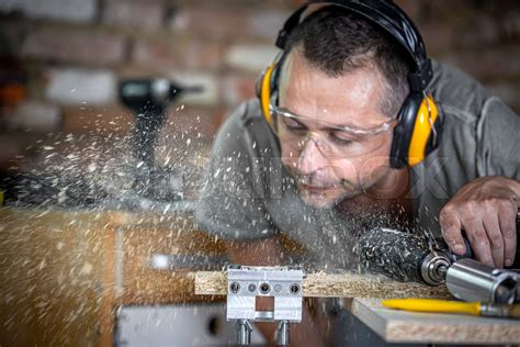 A male joiner blows wood off a board. | Stock image | Colourbox