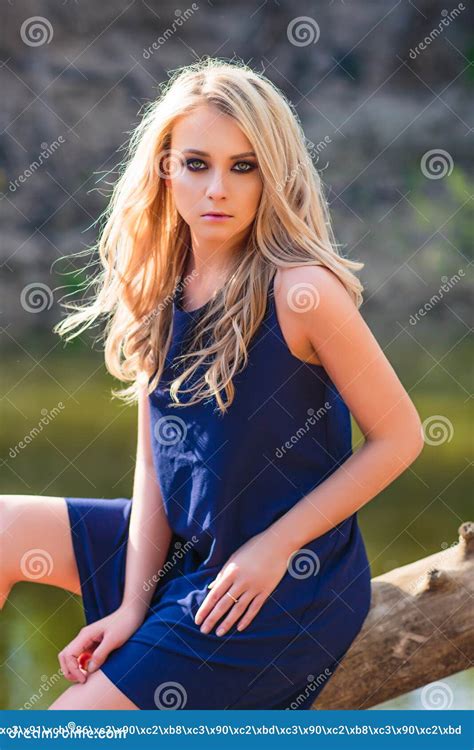 Belle Jeune Femme Blonde En Mini Robe Bleue Et L Eau Florale De Position Et D Essai De Couronne