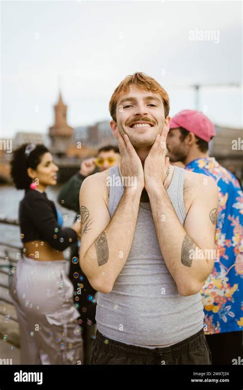 Portrait Of Smiling Gay Man Touching Face While Standing Near Friends Stock Photo Alamy