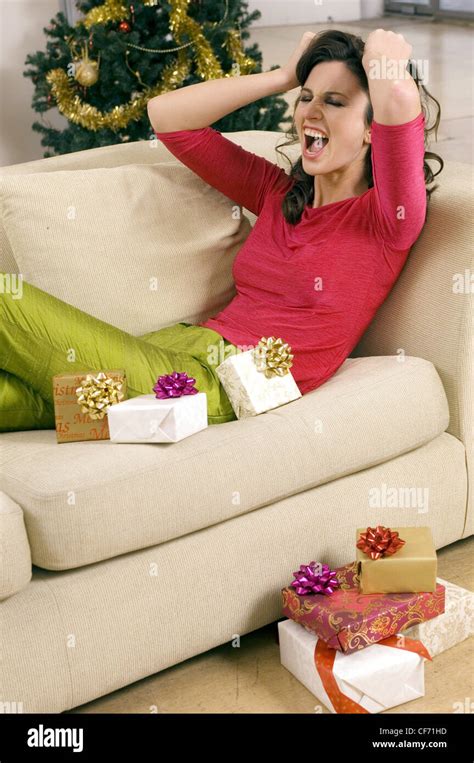 Female Brunette Wavy Hair Wearing Bright Pink Top Lime Green Silk Trousers Sitting On Sofa