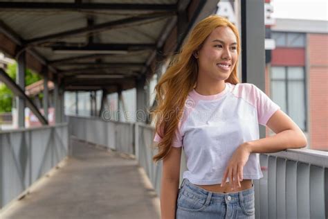 Portrait Of Beautiful Asian Girl With Blonde Hair Smiling And Thinking Outdoors Stock Photo
