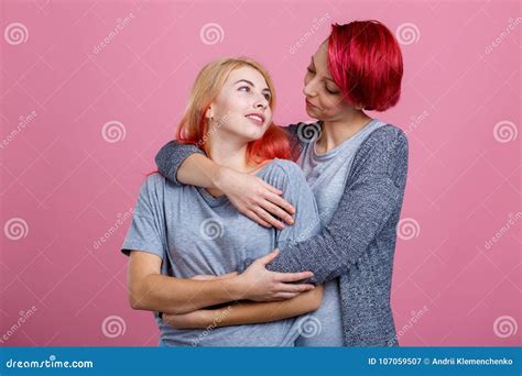 Two Lesbian Girls Embrace Each Other And Gaze At Each Other On A Pink Background Stock Image