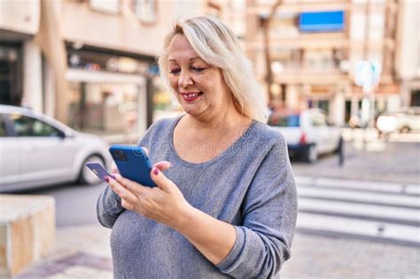 Middle Age Blonde Woman Smiling Confident Using Smartphone At Street Stock Image Image Of