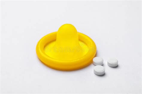 Yellow Condom And Birth Control Pills On Background Safe Sex Concept