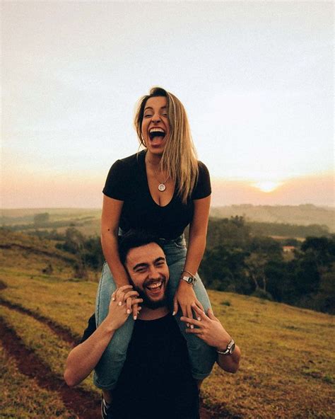 A Man Carrying A Woman On His Back In The Middle Of An Open Field At Sunset