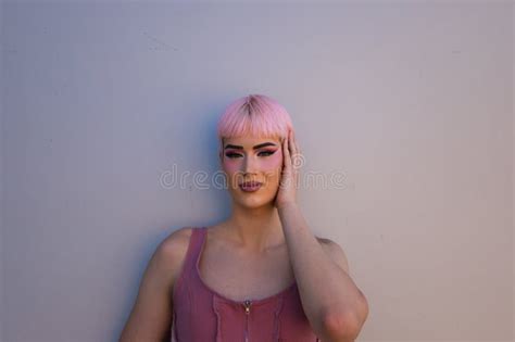 Retrato De Un Joven Gay Con Pelo Rosado Y Maquillaje Parado En Un Fondo Blanco Y Haciendo