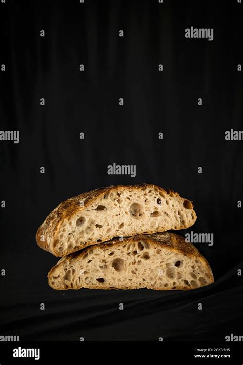 Bread cut in half against black background Stock Photo - Alamy