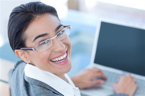 Empresaria sonriente que usa la computadora portátil Foto Premium