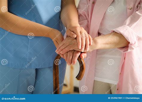 Elderly Woman With Walking Cane And Female Caregiver Indoors Closeup