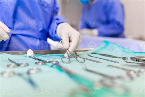 Surgeon picking up surgical tool from tray. Surgeon is preparing for