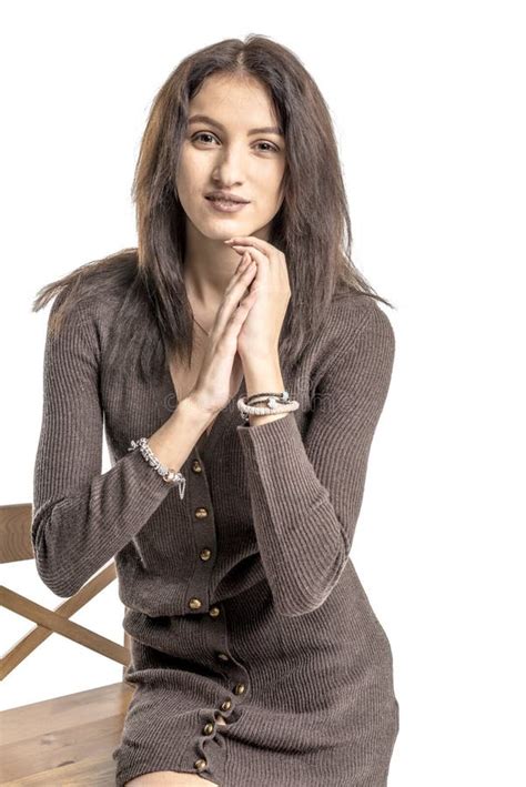Beautiful Brunette Girl Posing On A Chair In A Long Sweater And Woolen Stockings Stock Photo