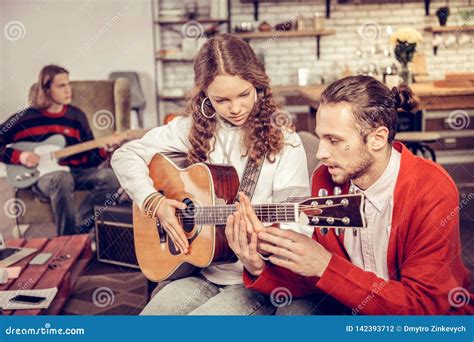 Tutor Teaching Teenagers To Play The Guitar In The Living Room Stock