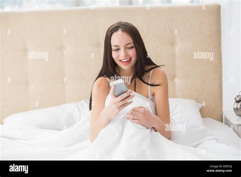 Pretty Brunette Sending A Text On Bed Stock Photo Alamy