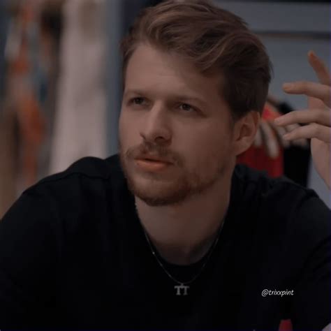 A Man In Black Shirt Sitting Down With His Hand On His Head And Looking