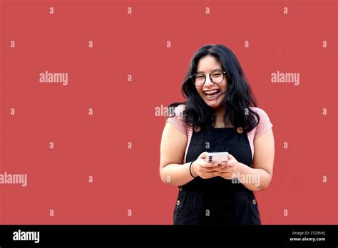 Brunette Latina Teen Woman With Eyeglasses And Brackets Uses Her Cell Phone To Text Shop And