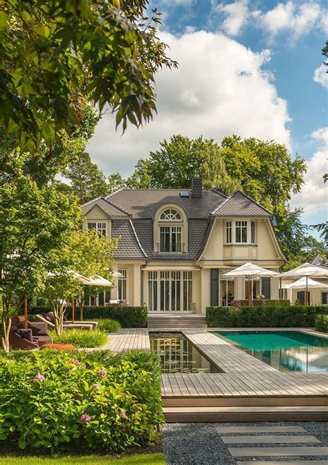 A Large House With A Pool In The Front Yard And Landscaping Around It