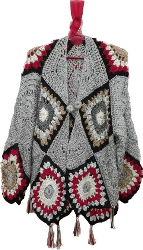 A Crocheted Jacket With Tassels On The Collar And Sleeves Hanging From