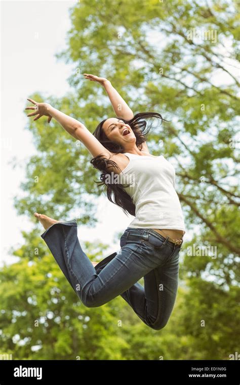 Excited Brunette Jumping In The Park Stock Photo Alamy