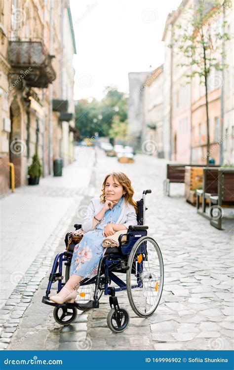 Jeune Fille Blonde Désactivée Attirante Dans La Robe Bleue Assis Dans Un Extérieur De Fauteuil