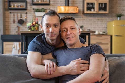 Pareja gay masculina abrazándose y mirando a la cámara en casa Foto Premium