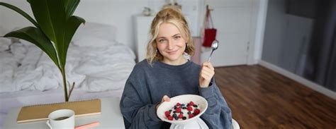 Portrait d une jolie femme blonde souriante qui prend son petit déjeuner dans sa chambre en
