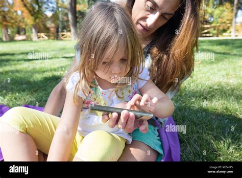 Four Years Age Blonde Girl Touching Mobile Smartphone Screen And Talking To Woman Mother