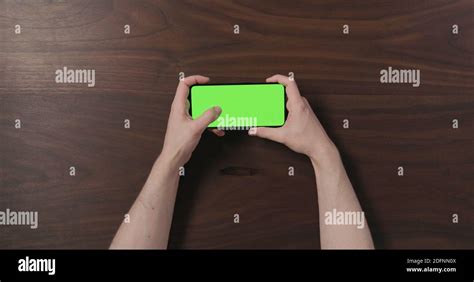 Top View Man Hand Use Smartphone With Green Screen Over Black Walnut