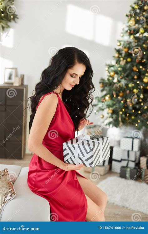 And Beautiful Leggy Brunette Model Woman In A Fashionable Red Dress Holding A Christmas